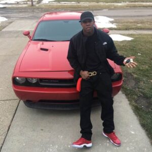 Lud Foe posing for a photo with his car