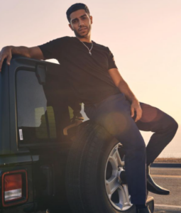 Mena Massoud posing for a photo with his car 